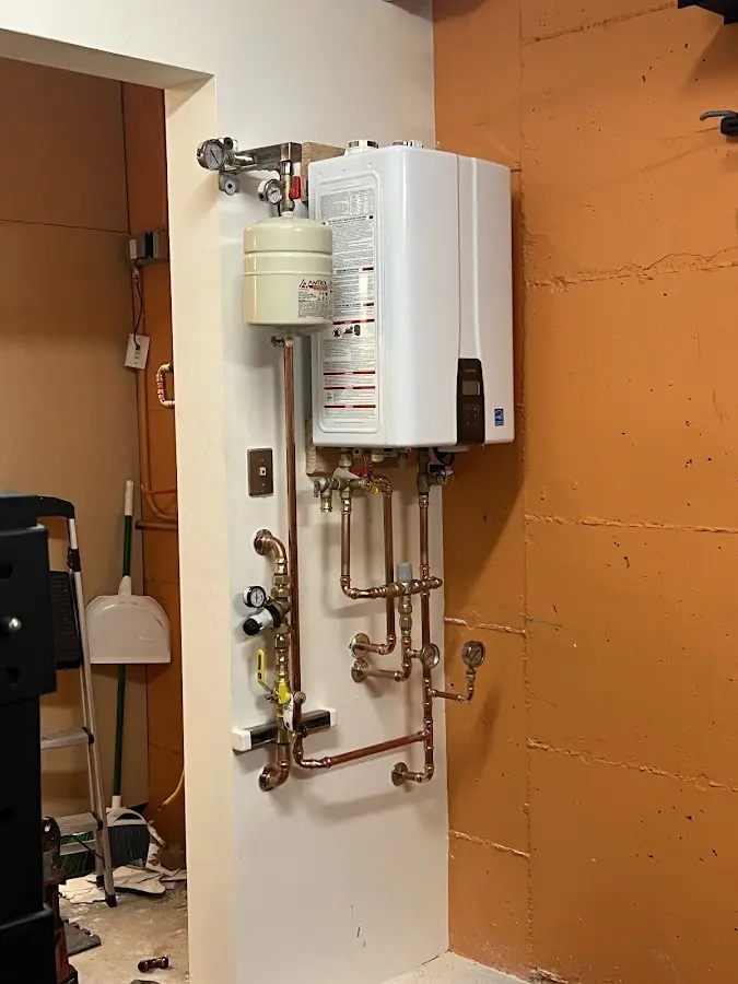 Plumbing technician inspecting water heater connections in Monfort Heights